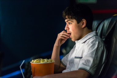 Çocuk sinemada film izlerken patlamış mısır yiyor