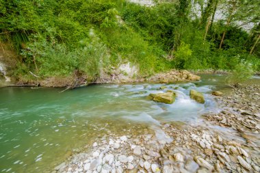 İtalya'da Emilia Romagna yeşil tepelerüzerinde bir nehrin yatağında berrak ve şeffaf suları