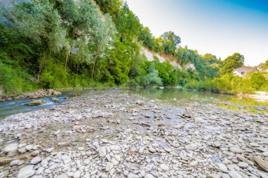 İtalya'da Emilia Romagna yeşil tepelerüzerinde bir nehrin yatağında berrak ve şeffaf suları