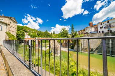 kayalık yığının etrafında akan nehir suları ve Romagna, İtalya tepelerde küçük bir köyde demir korkuluk ile görülen on ikinci yüzyıl köprüsü altında