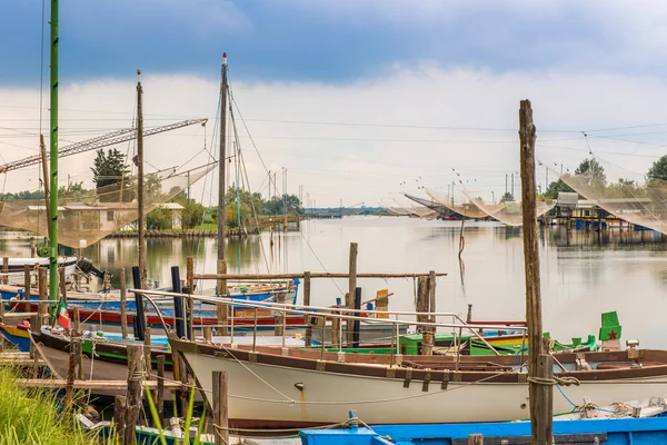 berthed old ships and fishing huts in the quiet of brackish lagoon in Italy