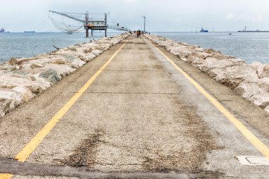 dalgakıran kayalar ile iskelede balıkçılar ve balıkçı kulübesi