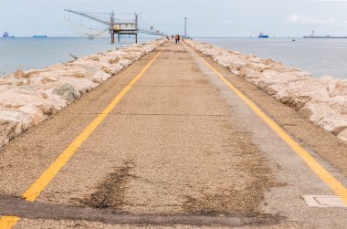 dalgakıran kayalar ile iskelede balıkçılar ve balıkçı kulübesi