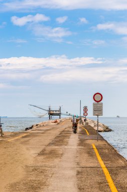 bisiklet, balıkçılar ve dalgakıran kayalar ile iskelede balıkçı kulübesi