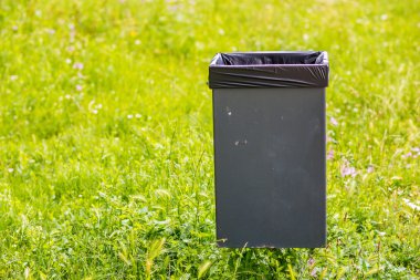 yeşil bir çayırda çöp kutusu
