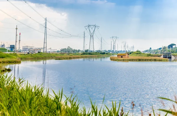 old hunting and fishing masonry lodge  on a lagoon near the industrial zone with factories and electricity pylons and weir