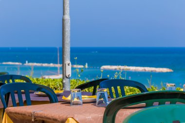 Plaj ve deniz panoraması ile kağıt masa örtüsü ve gözlük yüklü plastik bir masadan görünümü