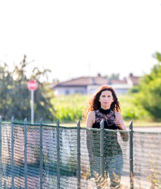 siyah dantel üst giyen ve yürürken vintage güneş gözlüğü tutan çekici olgun kadın