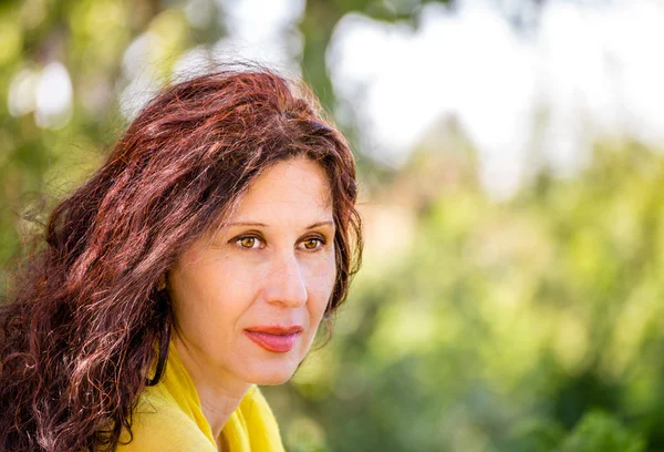 zarif ve göz alıcı menopozal kadın olgun cilt ile yüzünde yaşlanma belirtileri gösteren yeşil bir parkta gülümsüyor