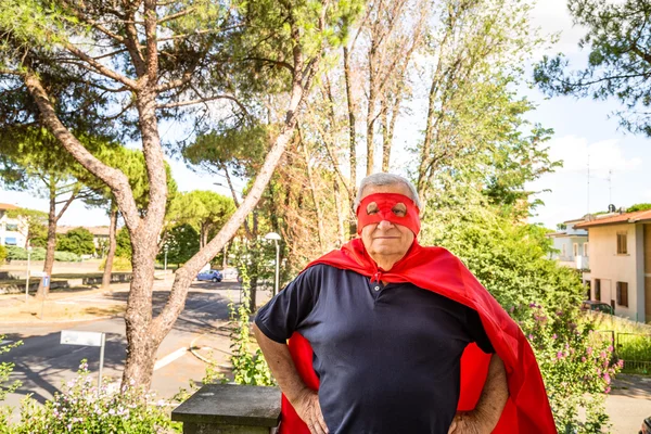 Старший позує як супергерой з червоним платтям і маскою — стокове фото