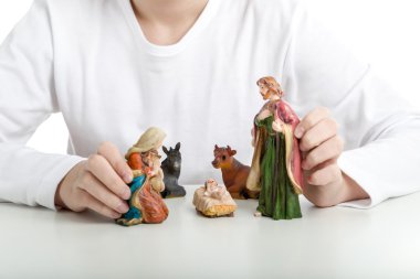 Bir çocuk Kutsal Aile heykeli bir Noel beşik içinde tutar. 