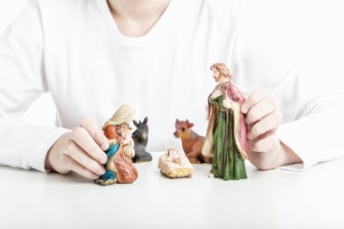 Bir çocuk Kutsal Aile heykeli bir Noel beşik içinde tutar. 