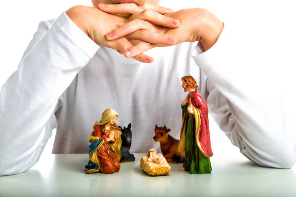 Ein Junge beschützt die heilige Familie in einer Weihnachtskrippe mit seiner Hand — Stockfoto