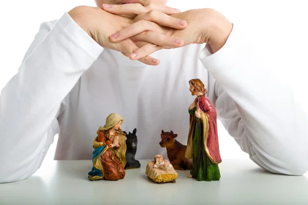 Un niño protege a la Sagrada Familia en una cuna de Navidad usando su han —  Fotos de Stock