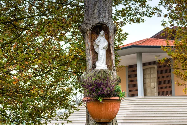 Nossa Senhora Estátua no tronco em frente à igreja — Fotografia de Stock