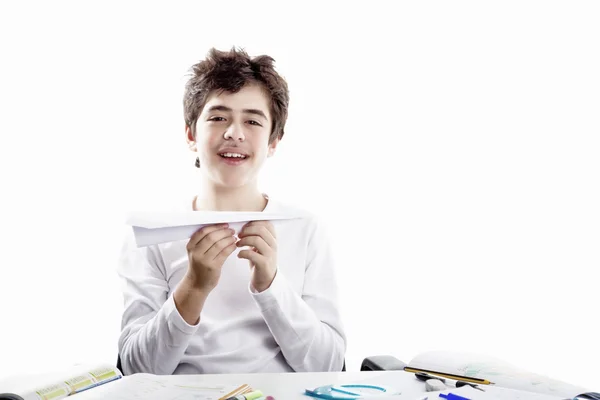 Latin boy playing with a paper airplane sitting in front of home — Stock Photo, Image