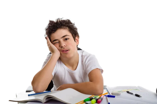 Tired boy holds his face in front of homework on blank book — Stock Photo, Image