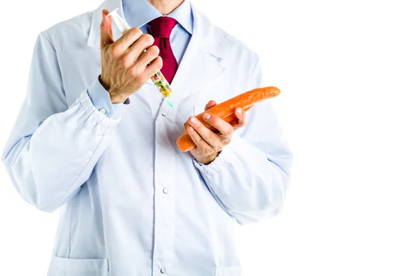Doutor em casaco branco fazendo uma injeção para cenoura laranja — Fotografia de Stock