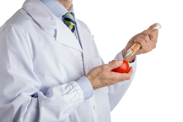 Férfi orvosi fehér kabátot teszi egy injekciót vörös érett paradicsom — Stock Fotó