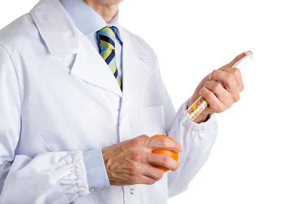 Homem de casaco branco médico faz uma injeção para laranja — Fotografia de Stock