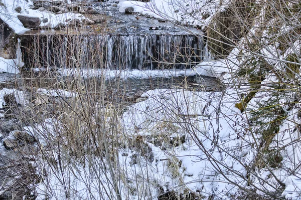 Gebirgsbach inmitten von Schnee und Felsen am Ufer des — Stockfoto