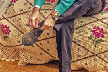 oturan orta yaşlı adam ayakkabı bağı bağlar