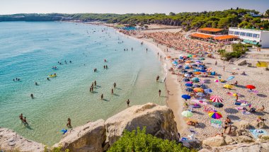 İtalya'da Puglia Salento kıyısında kayalık koy yakınlarındaki koyda plaj tesisleri