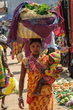 Koraput, Hindistan - Şubat 2021: Kondh kabilesinden Adivasi kadın çocuğu ile 21 Şubat 2021 'de Odisha, Hindistan' da Koraput pazarında sebze alışverişi yaptı..