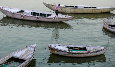Varanasi, Hindistan - Nisan 2021: Bir adam 5 Nisan 2021 'de Uttar Pradesh, Hindistan' da Ganga Nehri 'nde teknesini hazırlıyor..