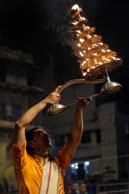 Varanasi, Hindistan - Nisan 2021: Hindistan 'ın Uttar Pradesh şehrinde 5 Nisan 2021 tarihinde Dashashwamedh Ghat' ta Ganga Aarti dini ritüelini gerçekleştiren Hindu rahip.
