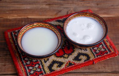 Mare and camel milk in bowls on a rustic background clipart