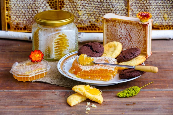 蜂窝里的蜂蜜 桦枝上的蜂窝里的野蜜 盘子里的饼干和切碎的梳子 木制背景的蜂蜜 — 图库照片