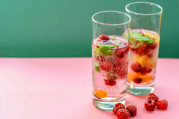 Detox drink on a pink and green background. Fresh raspberry lemonade