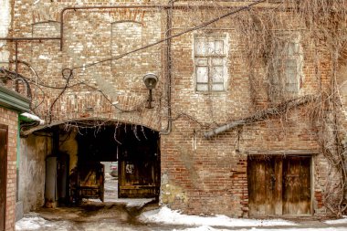 Avlunun eski girişi eski kırmızı tuğladan bir evin içine inşa edilmiş bir kemerle, kışın bir gecekondu mahallesi.