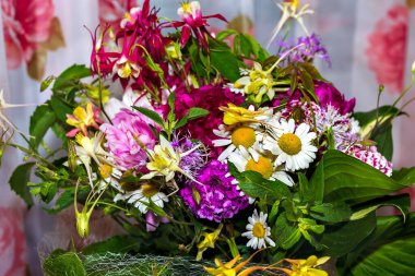 İçinde şakayık, akuleji ve büyük yeşil yapraklar olan büyük, renkli kır çiçekleri. İç kısımdaki bir vazoda tatil için bir hediye.