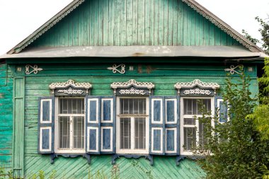 Rus köyünde oyulmuş pencereli eski yeşil ahşap bir ev.