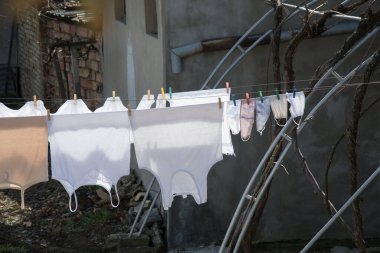 Açık havada çamaşır kurutma, gündüz yıkanmış maskeler arka bahçede ipte asılı duran morluklara karşı, kentsel arka plan.