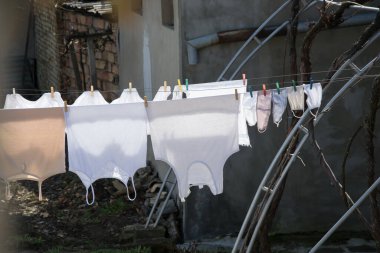 Açık havada çamaşır kurutma, gündüz yıkanmış maskeler arka bahçede ipte asılı duran morluklara karşı, kentsel arka plan.