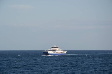 Mavi ve beyaz feribot, seyir halinde ve durgun mavi su, güzel mavi gökyüzü. Akdeniz tatil konsepti, feribot ulaşımı, denizde gemi.