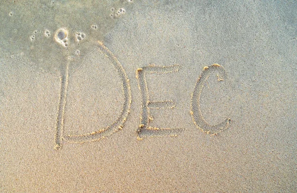 Dezember oder Dezember Wort am Strand Sand. Dezember auf gelbem Sand gedruckt, Draufsicht. — Stockfoto