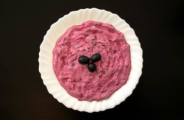 Meşhur geleneksel Arap mutfağı. Koyu ahşap arka planda beyaz bir tabakta pancar humusu. Arap pancarı ve nar işçiliği ya da zeytinli yoğurt.