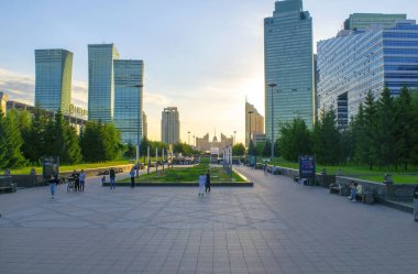 Nur-Sultan - Kazakistan: 10 Haziran 2021: Parklı Nur-Sultan Merkezi, Nurjol Bulvarı 'ndaki Keruen alışveriş merkezi ve gökdelenler, yazın gün batımında insanlar.