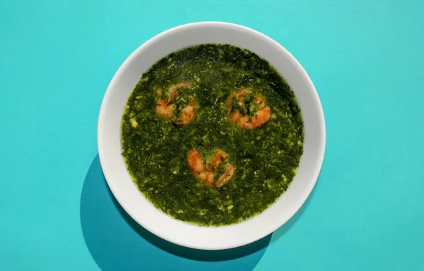 Famous traditional Arabic cuisine. Molokhia green soup with shrimps on blue background. Flat lay, top view. Moroheiya — Stock Photo, Image