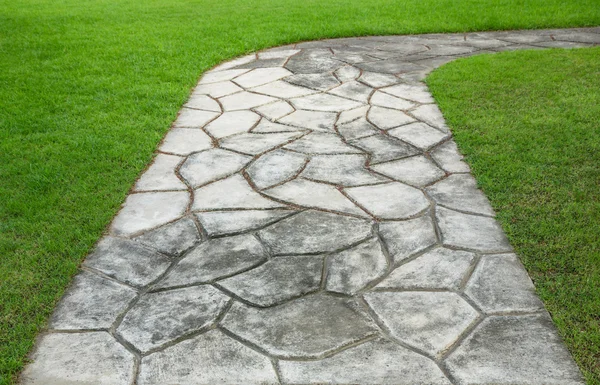 Stenen blockera promenad väg i parken med grönt gräs — Stockfoto