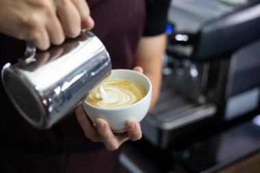 Man Barista 'nın latte sanatı yaparken yakın çekimi.