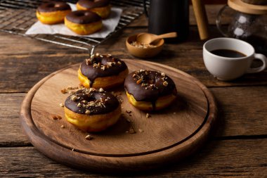 Ahşap masa arkasında çörek ve kahve.