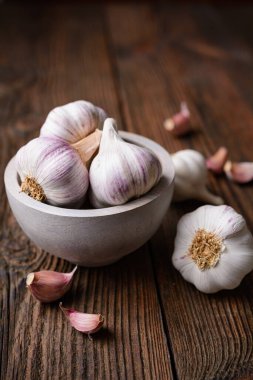 Doğal antibiyotik, sade ahşap arka planda karanfilli taze sarımsak soğanı.