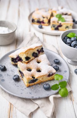 Lezzetli ve kolay yaban mersinli kek üzerine pudra şekeri serpiştirilmiş.