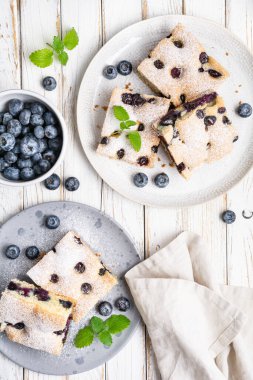 Lezzetli ve kolay yaban mersinli kek üzerine pudra şekeri serpiştirilmiş.