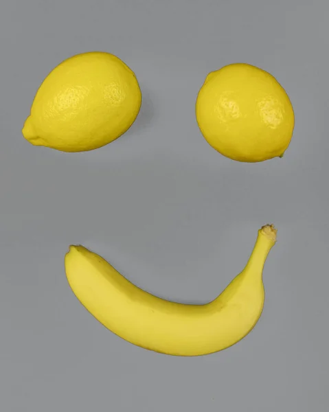 Muz meyvesi ve gri arka planda iki limon..